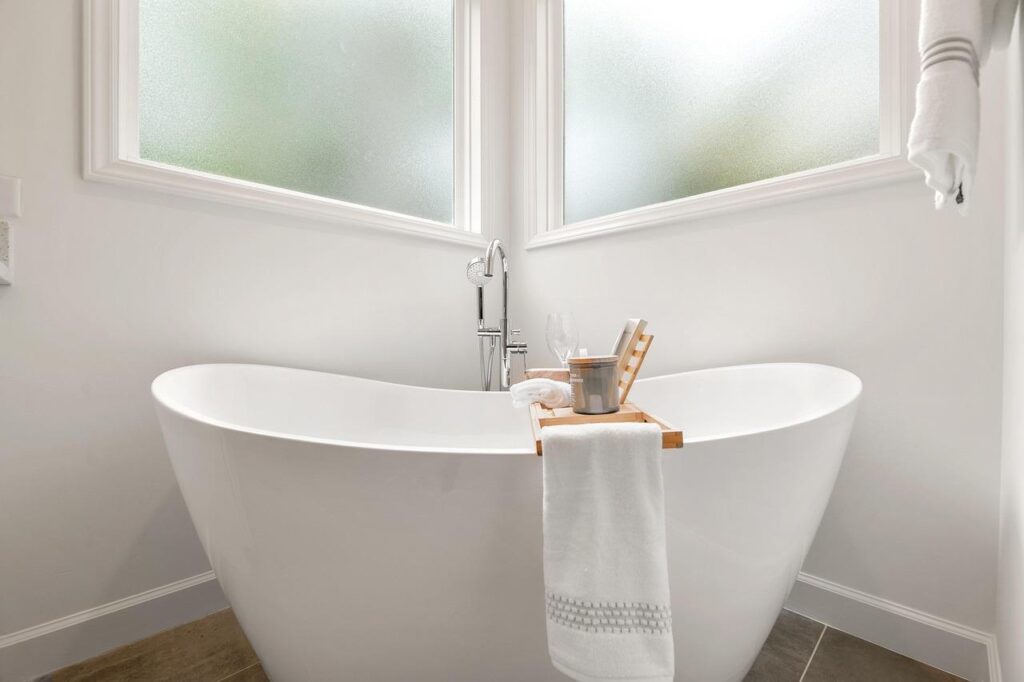 Japandi badkamer met natuurlijke materialen, zachte kleuren en een luxe bubbelbad dat rust en eenvoud uitstraalt